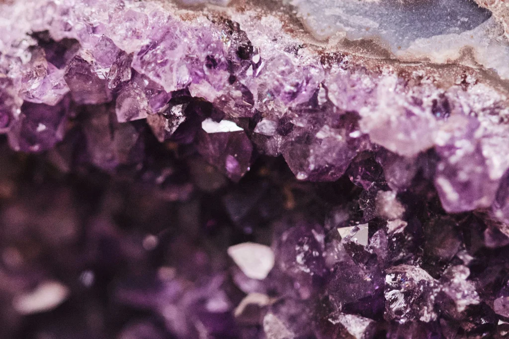 Amethyst crystal cluster on a decorative surface under soft lighting.