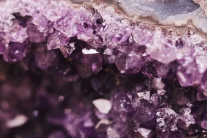 Amethyst crystal cluster on a decorative surface under soft lighting.