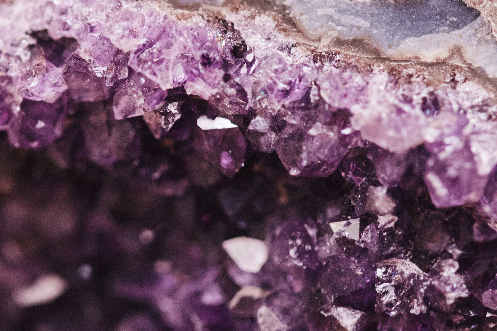 Amethyst crystal cluster on a decorative surface under soft lighting.