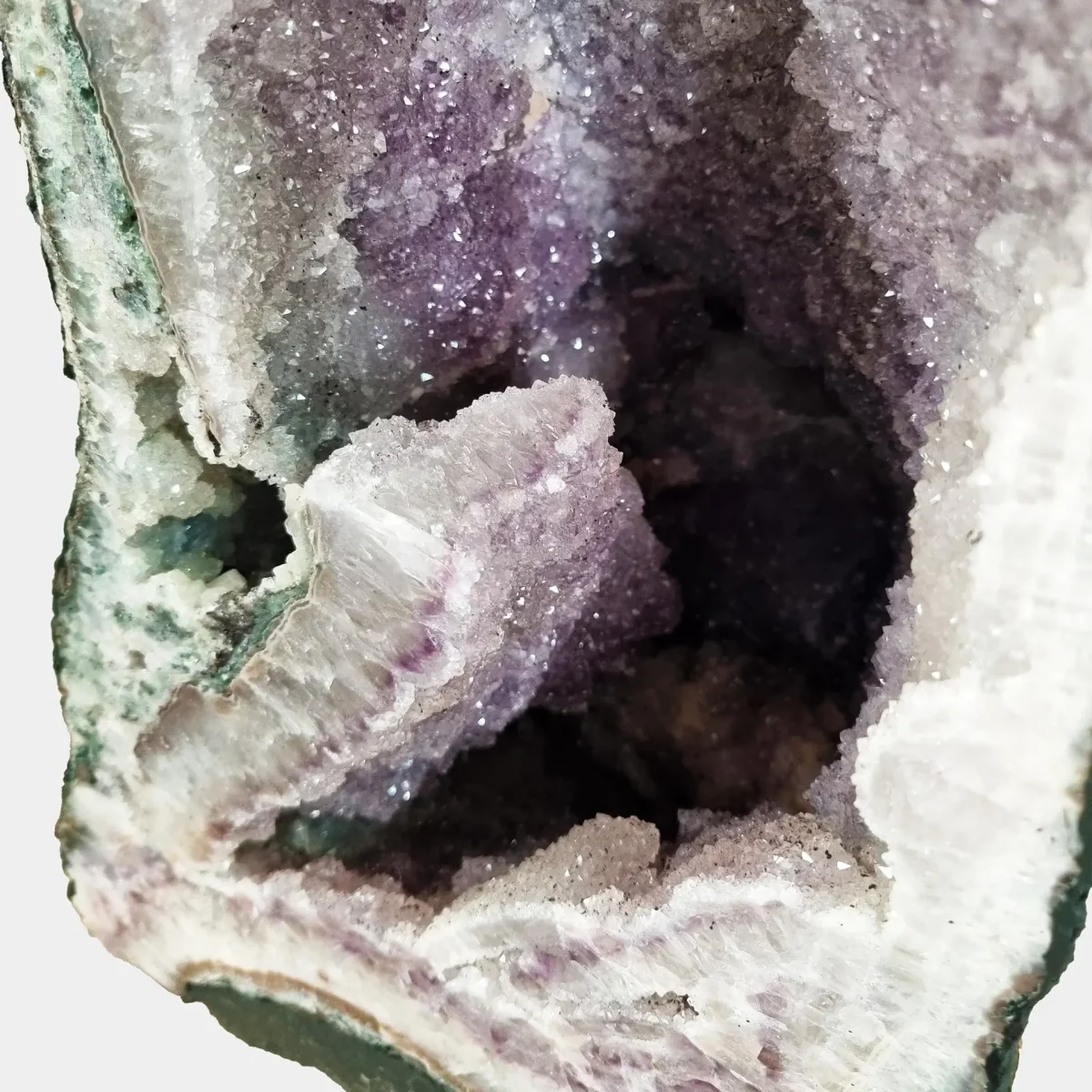 Detailed view of the lower crystal section showing dense violet points and subtle quartz transitions within the geode’s base.