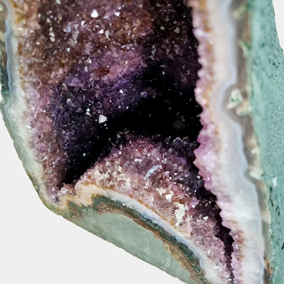 Bližnji pogled v notranjost geode razkriva sijaj vijoličnih kristalov in nežne prehode med plastmi kremena.