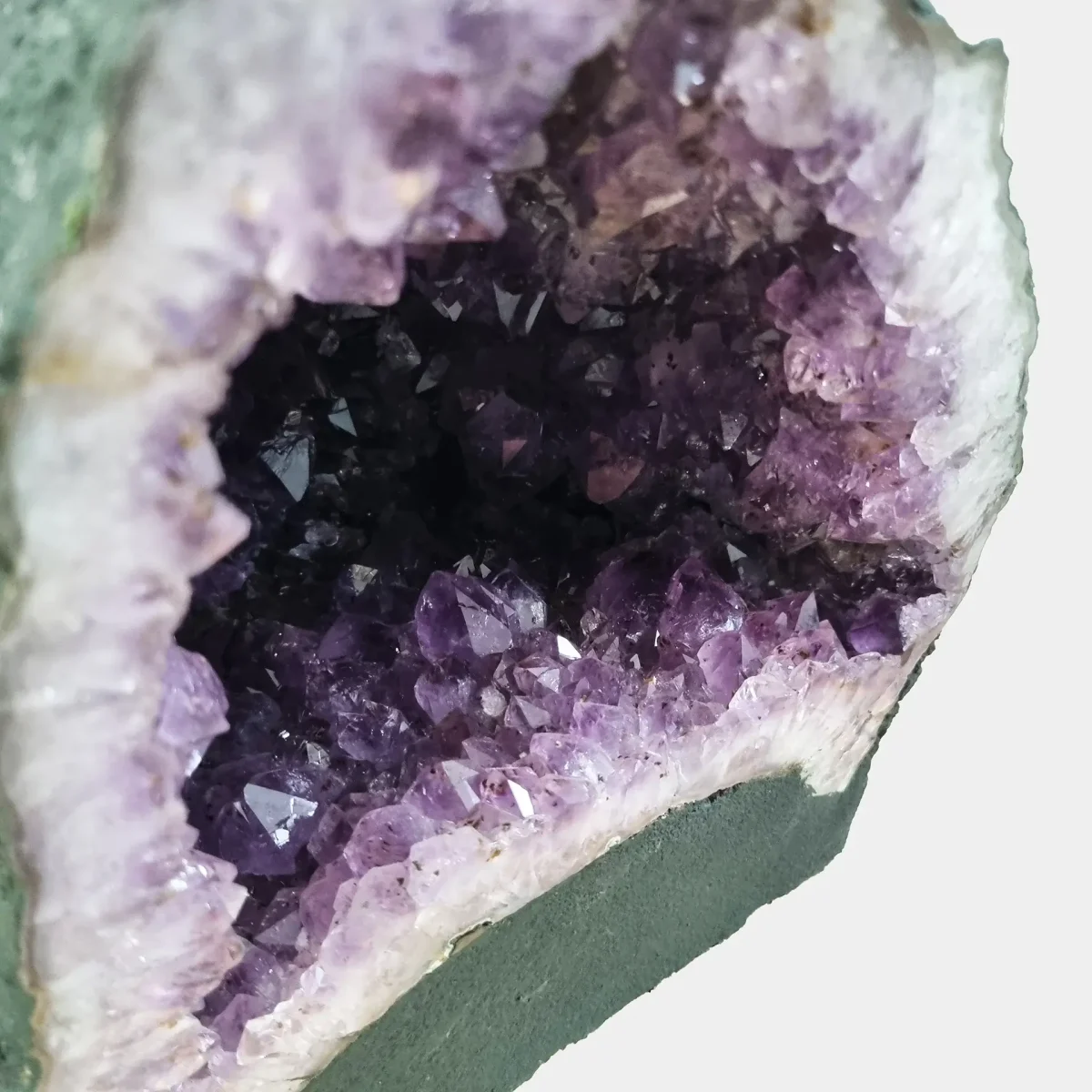 Pogled v notranjost razkriva bogate vijolične odtenke, drobno kristalno zgradbo in nežne prehode med plastmi kremena.