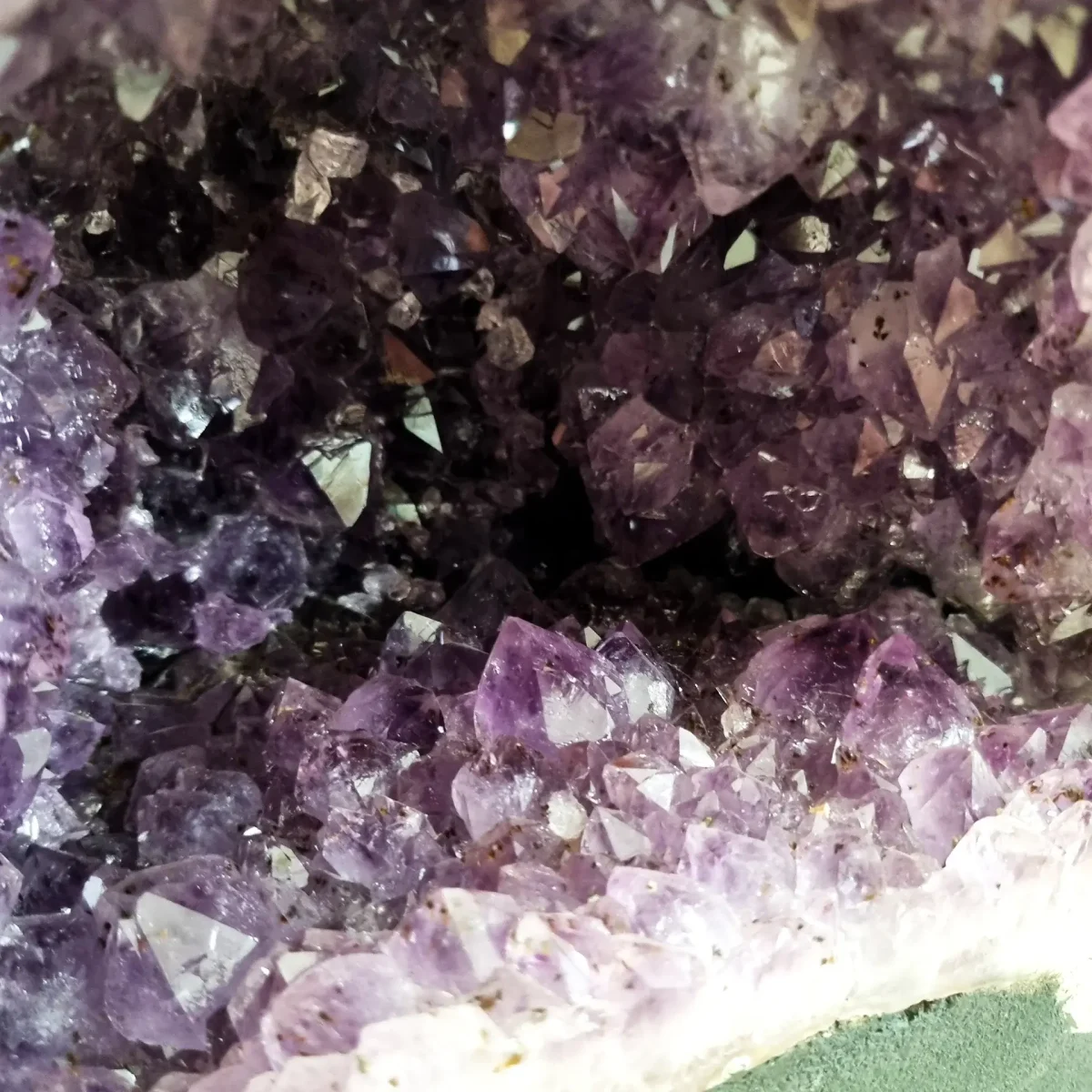 Bližnji posnetek ametistovih kristalov razkriva njihovo naravno geometrijo, sijočo prosojnost in globok, žareč sijaj.