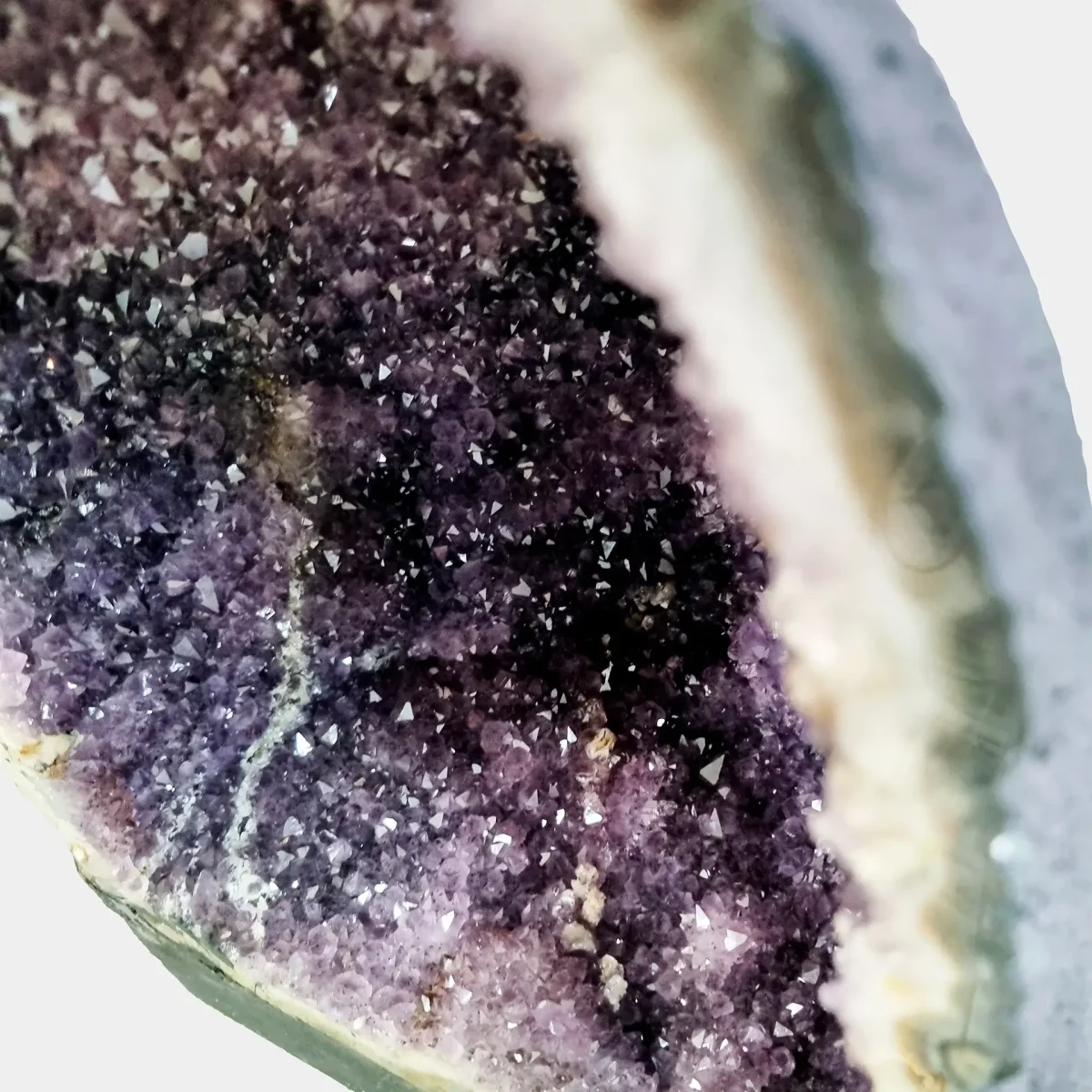 Pogled v notranjost geode razkriva živo kristalno globino in nežne prehode v notranji ametistovi komori.