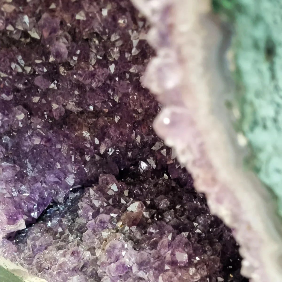 Bližnji pogled razkriva bleščeče skupine ametistovih kristalov in naravno prosojnost notranje komore.