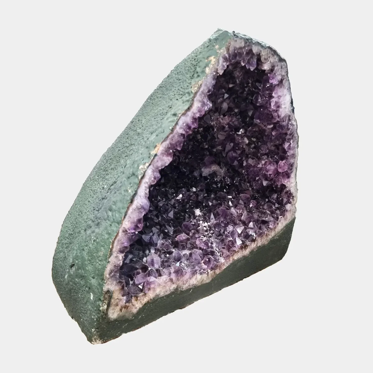 Prvi stranski pogled poudarja zaobljeno obliko geode in harmonično globino kristalov z nežnimi odsevi svetlobe.