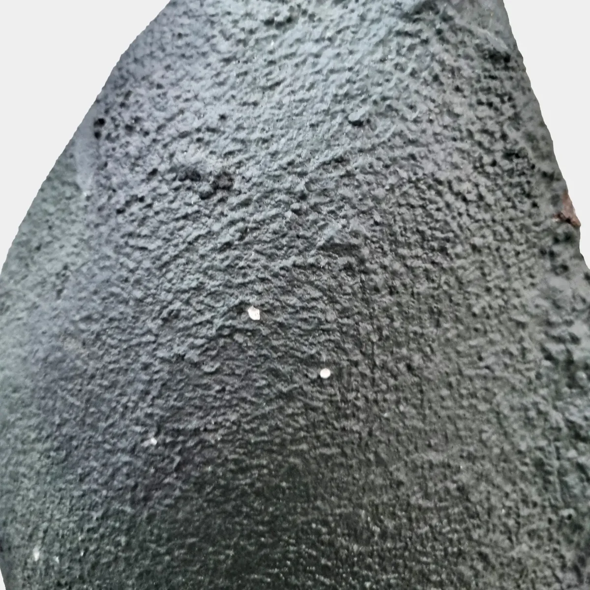 Zadnji pogled na ametistovo geodo prikazuje naravno bazaltno površino in čvrsto, nepolirano zunanjost.