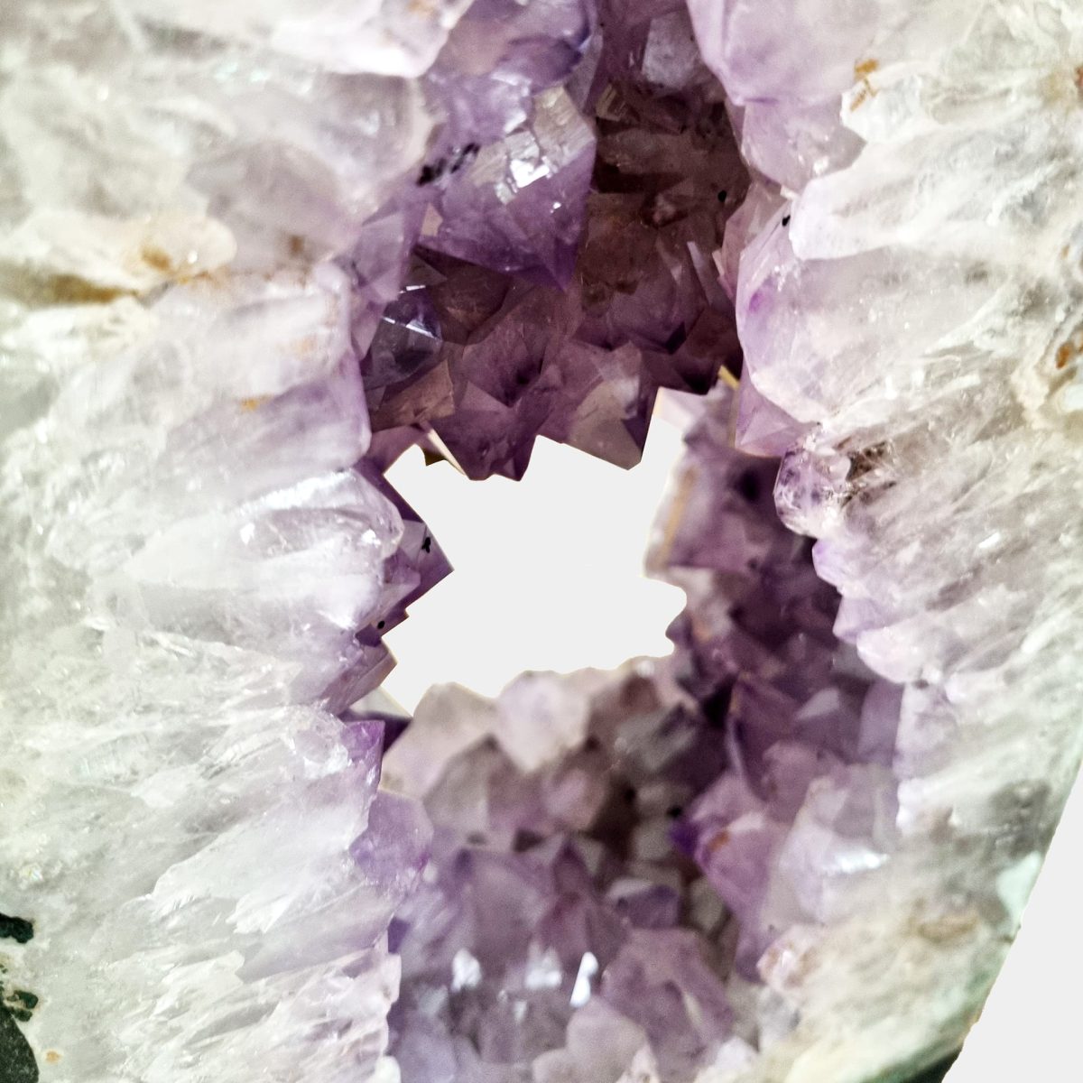 Bližnji posnetek notranjih sten razkriva njihovo čistost, ostrino kristalnih oblik in sijočo globino vijoličnih tonov.