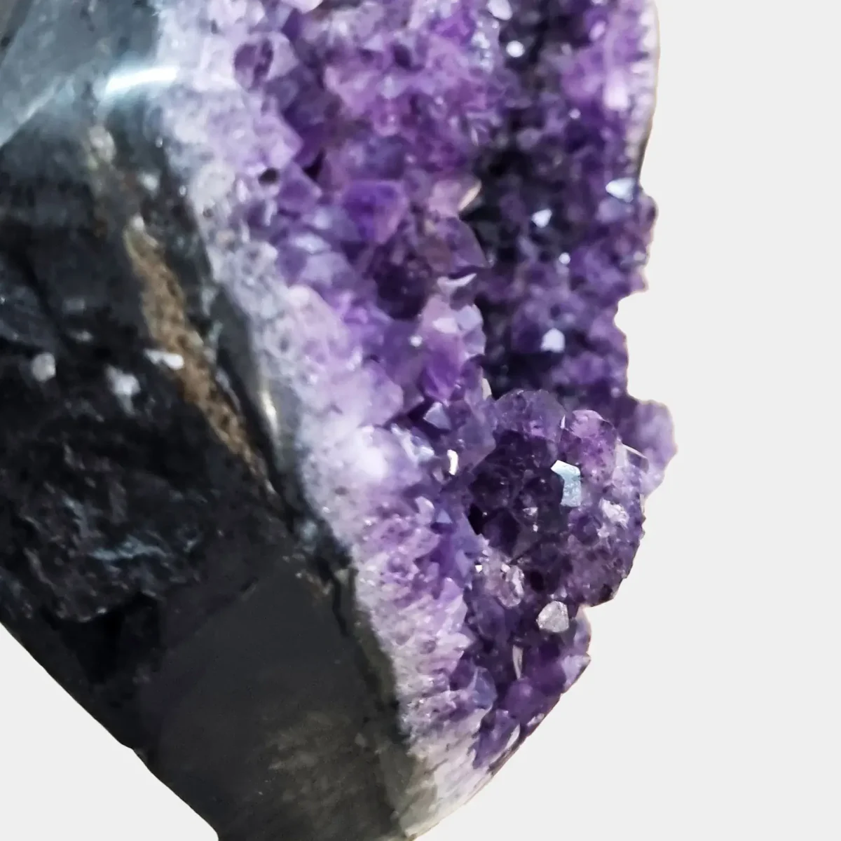 Povečan posnetek sijočih, globoko vijoličnih kristalov ametista – razkošen dekorativni in energijski kos za dom.