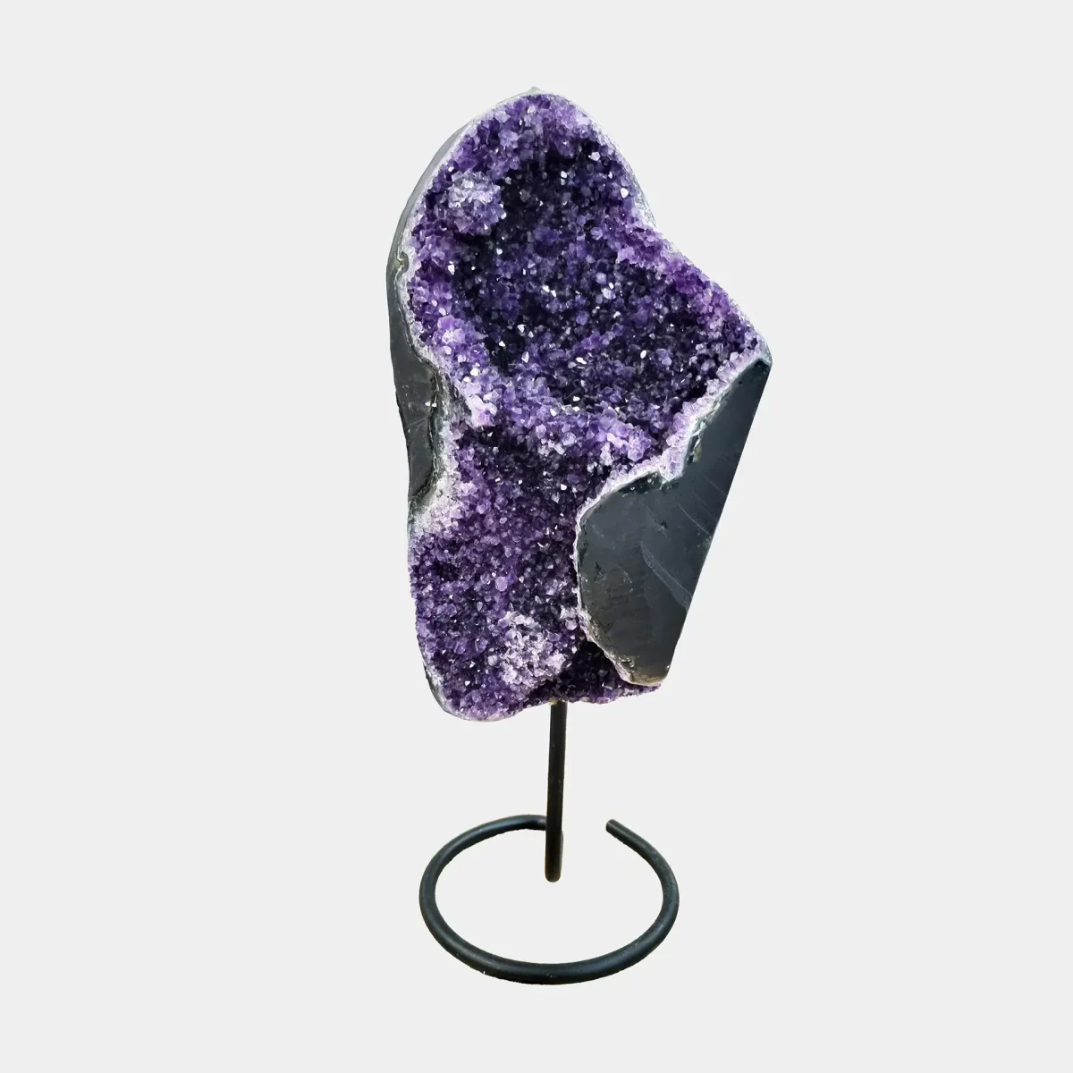 Ročno izbrana luksuzna ametistna geoda na elegantnem črnem kovinskem stojalu.