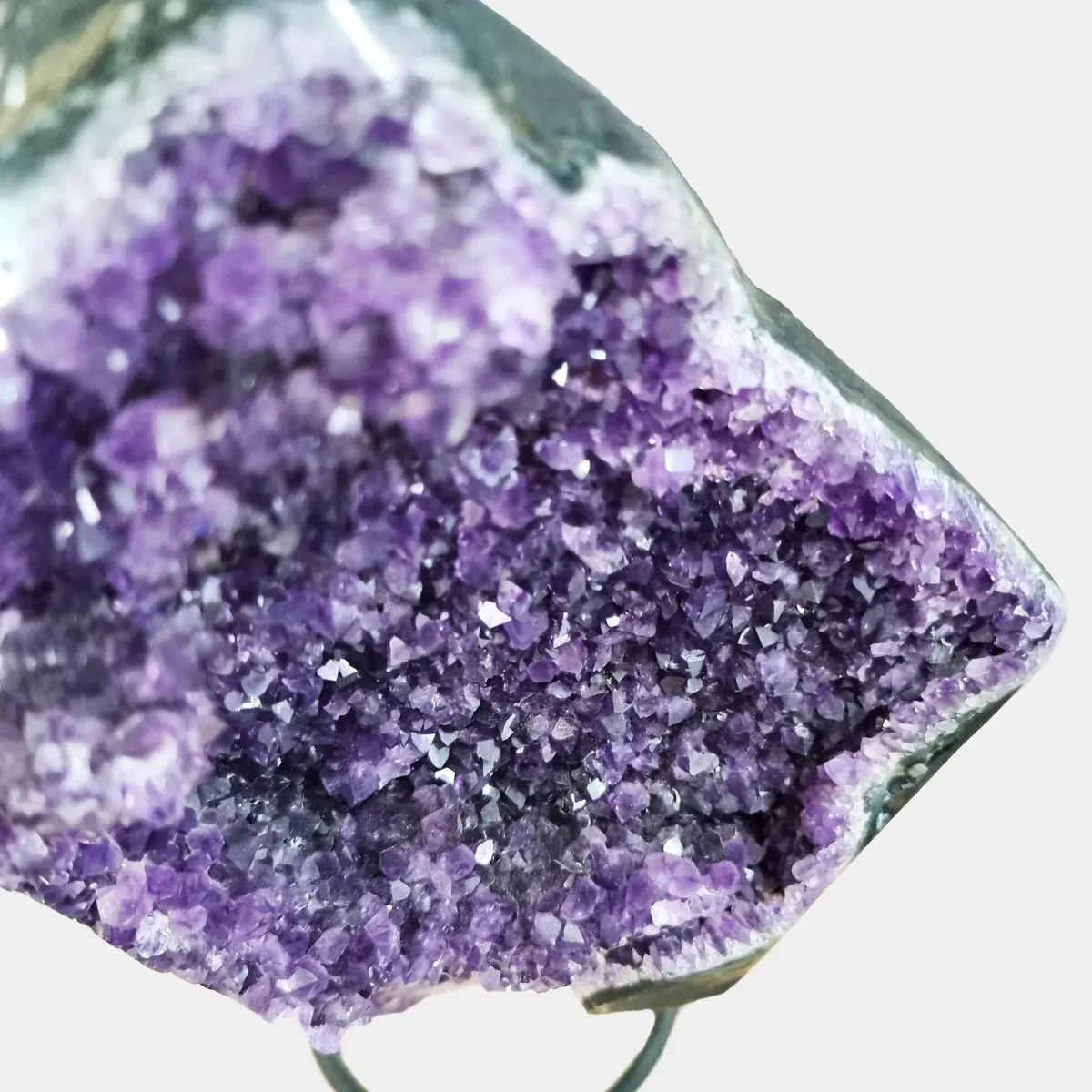 Bližnji posnetek žarečih, globoko vijoličnih kristalov ametista – razkošen dekorativni in energijski kos za dom.