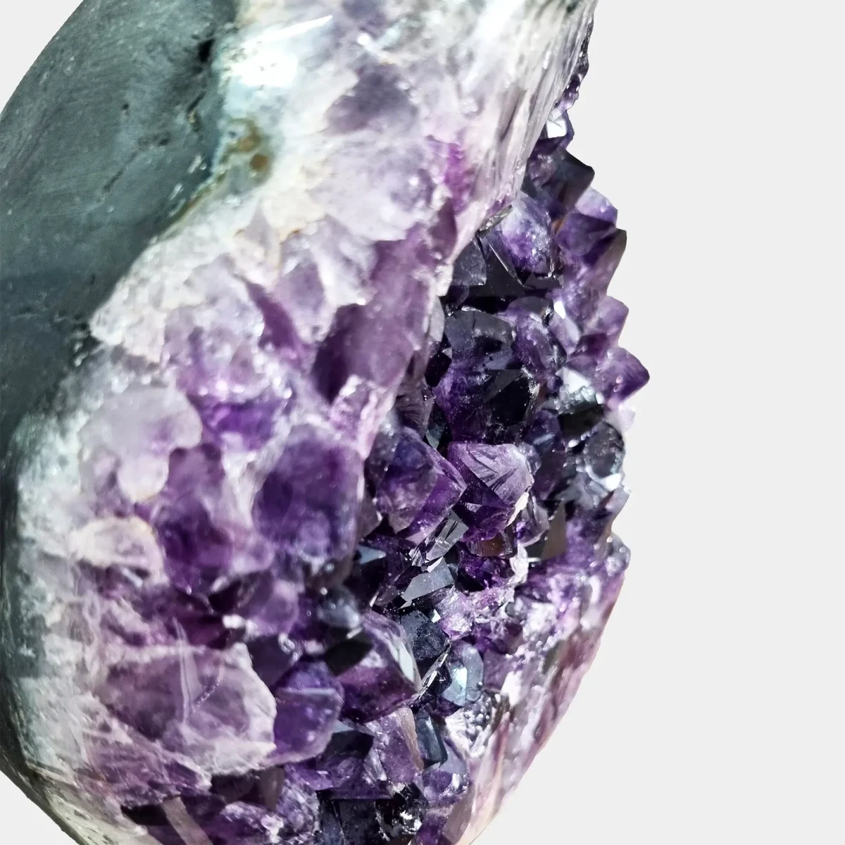 Makro pogled razkriva preliv med belim kremenom, vijoličnim ametistom in poliranim bazaltnim robom.