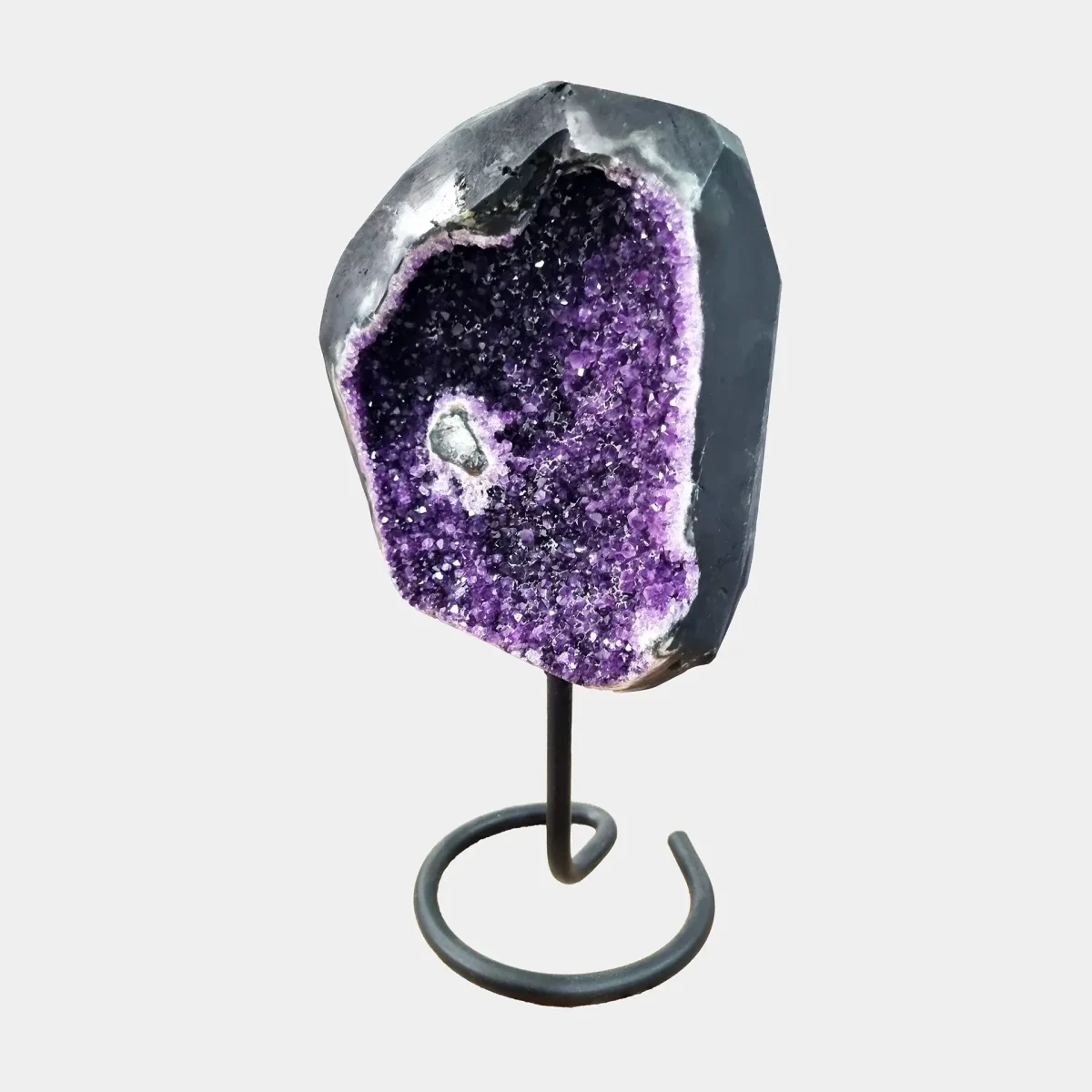 Stranski pogled razkriva nežno zaobljene obrise geode z globoko vijoličnim jedrom in kremenovimi robovi.