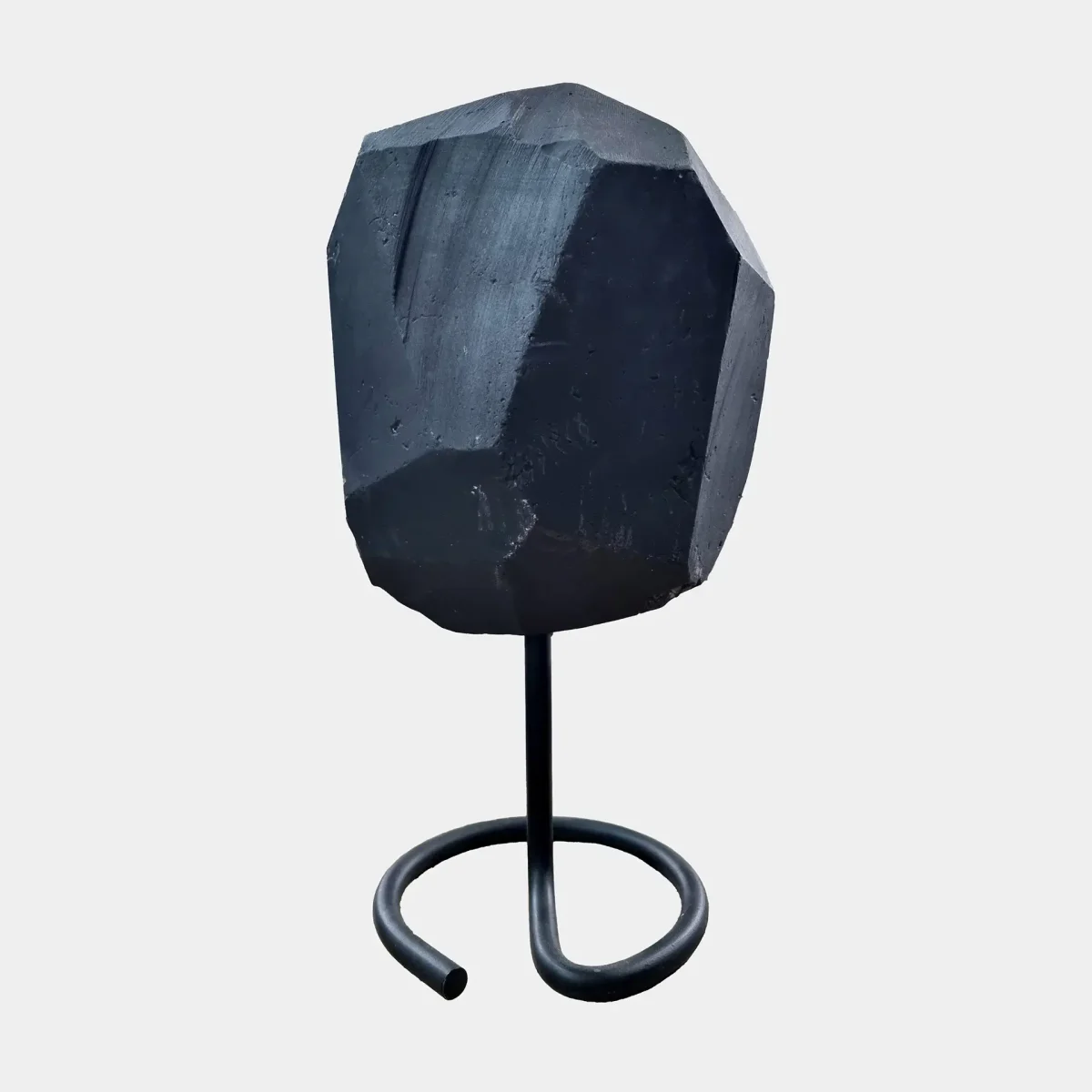 Hrbtni pogled prikazuje polirano bazaltno površino in skulpturalno geometrijsko obliko geode.