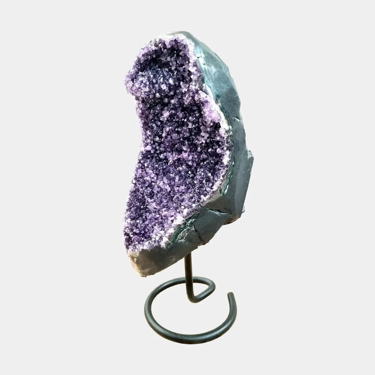 Stranski pogled poudarja elegantno ukrivljenost ametistne geode in prefinjeno globino kristalov.