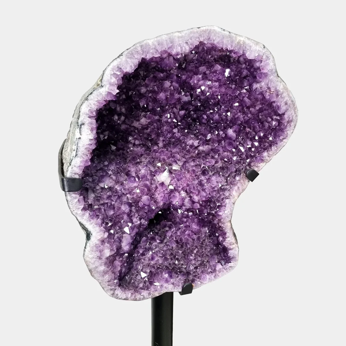 Poševen pogled prikazuje notranji sijaj ametista ter naravno bazaltno zunanjost.