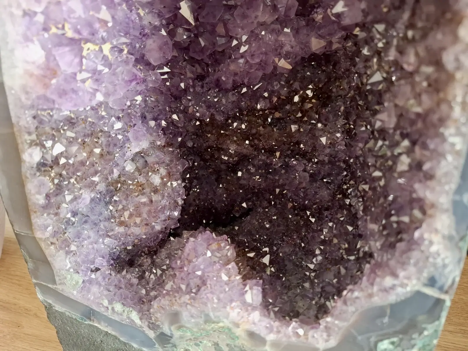 Bližnji pogled v notranjost ametistne geode z bleščečimi vijoličnimi kristali.