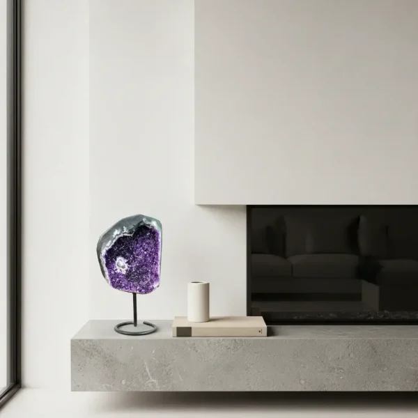 Ametistova geoda na stojalu št. 6 ob minimalističnem kaminu v sodobno opremljenem notranjem prostoru.