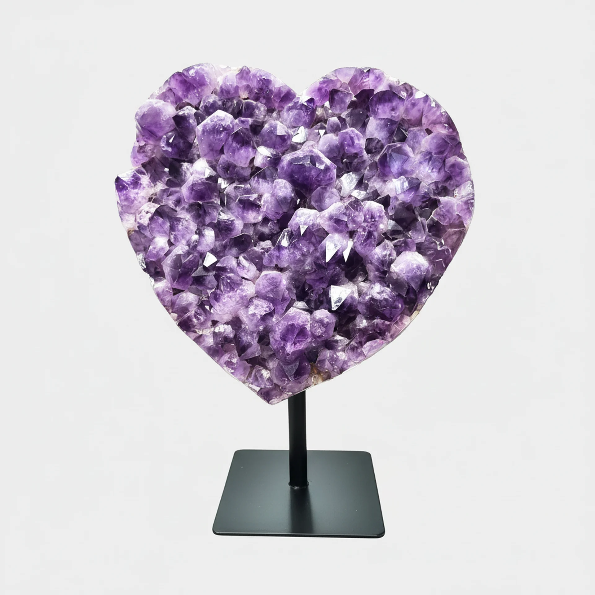 Amethyst Statement Piece N°2 – 54 cm – Front View Front view of a heart-shaped Amethyst cluster on a black metal stand with vivid violet crystals.