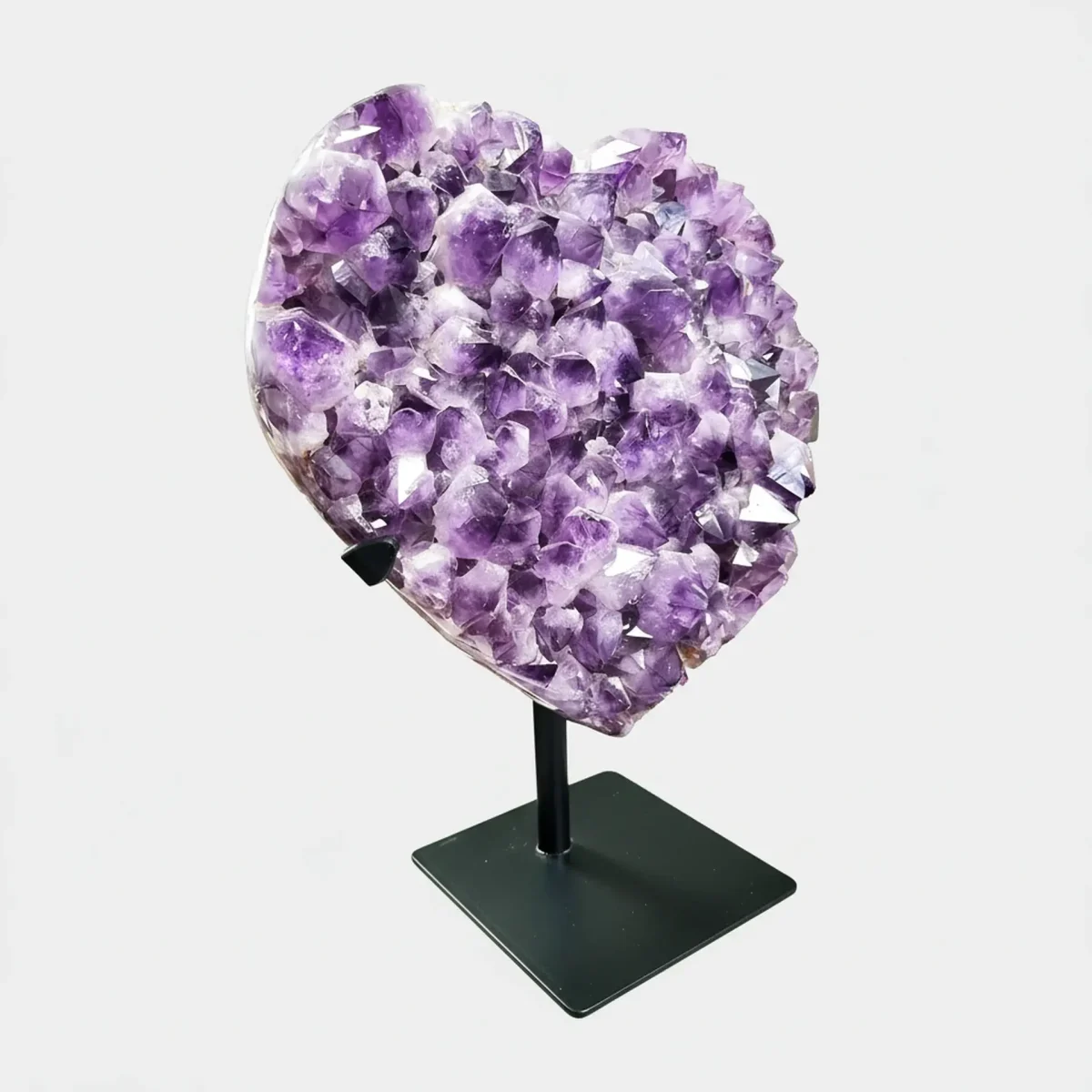 Drugi stranski pogled na srčasto oblikovan ametistov grozd na črnem stojalu, kjer se lepo vidijo plastenje kristalov in bogata struktura površine.