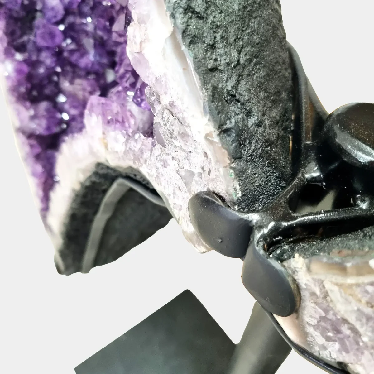 Bližnji posnetek po meri izdelanega kovinskega stojala, ki trdno in elegantno podpira dvokrako ametistovo formacijo.