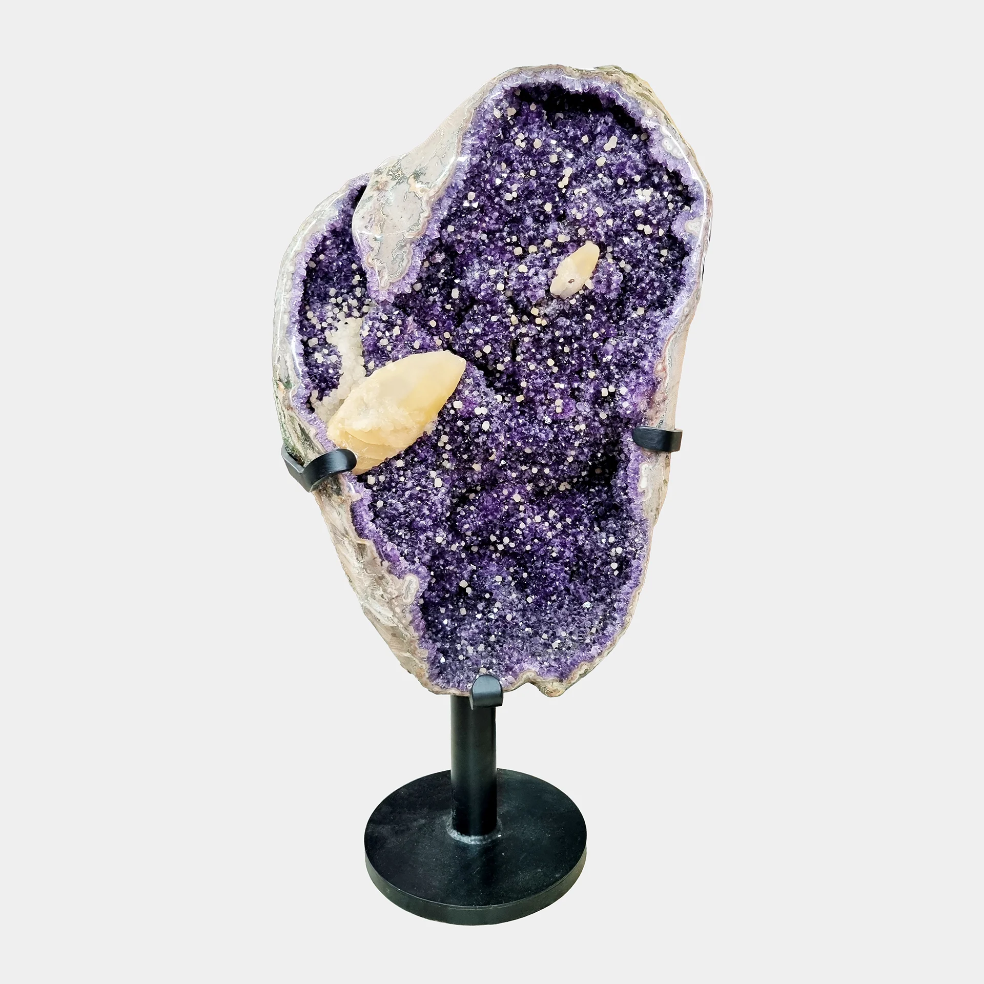 Amethyst Statement Piece N°4 – 101 cm – Front View Front view of a tall Amethyst geode with Calcite inclusions on a black stand showcasing deep violet crystals.