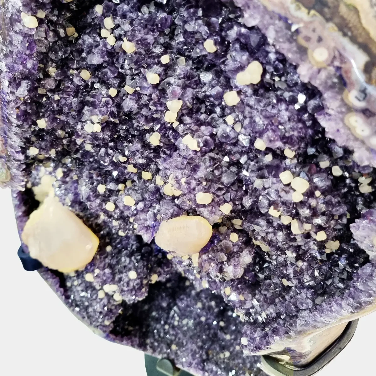 Makro pogled na ametistove kristale z belimi kalcitnimi izrastki, kjer se lepo vidijo drobne teksturne razlike in naravna igra barv.