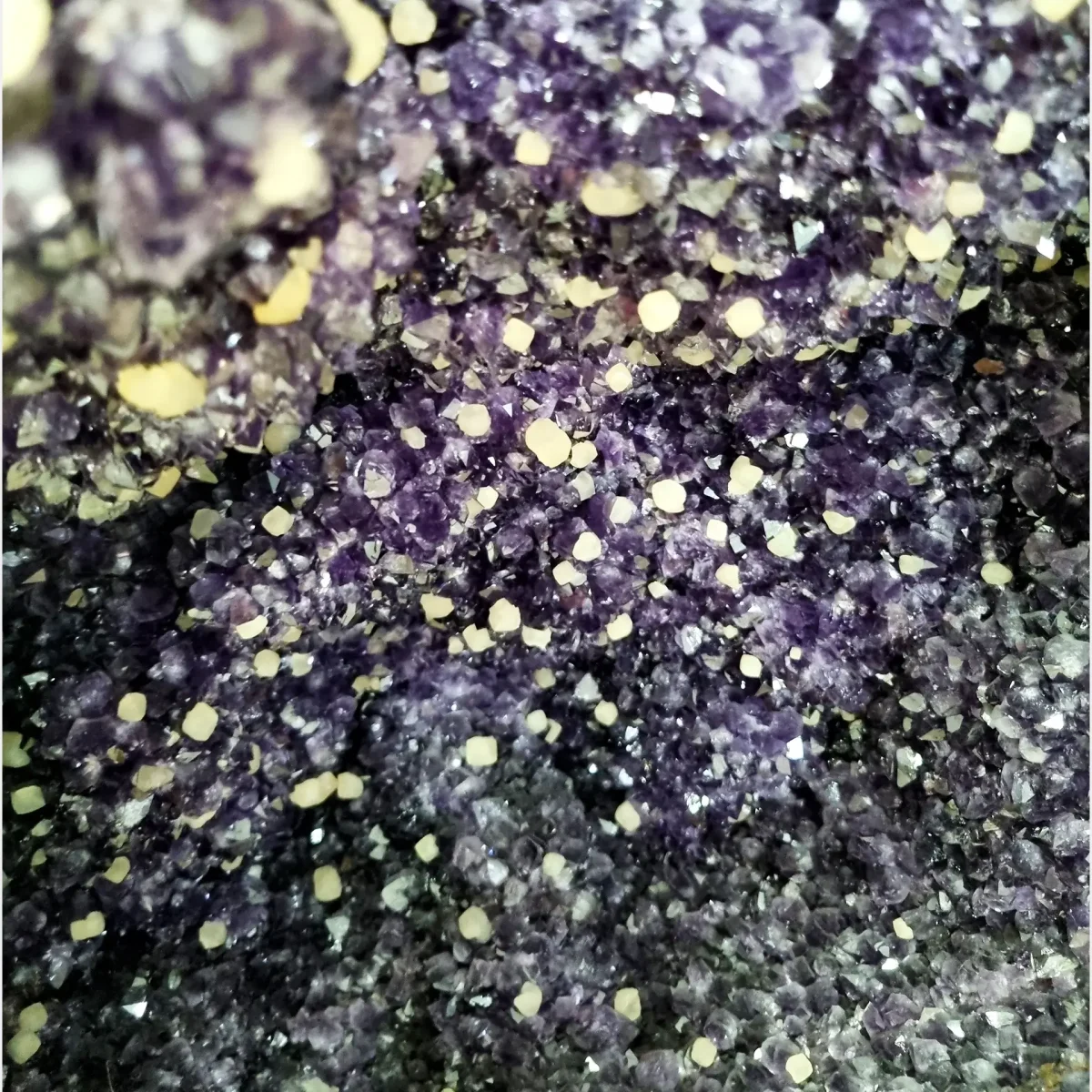 Bližnji posnetek drobnozrnatega ametista, prepredenega z nežnimi belimi mineralnimi vključki, ki poudarjajo naravno razgibanost kristalne strukture.