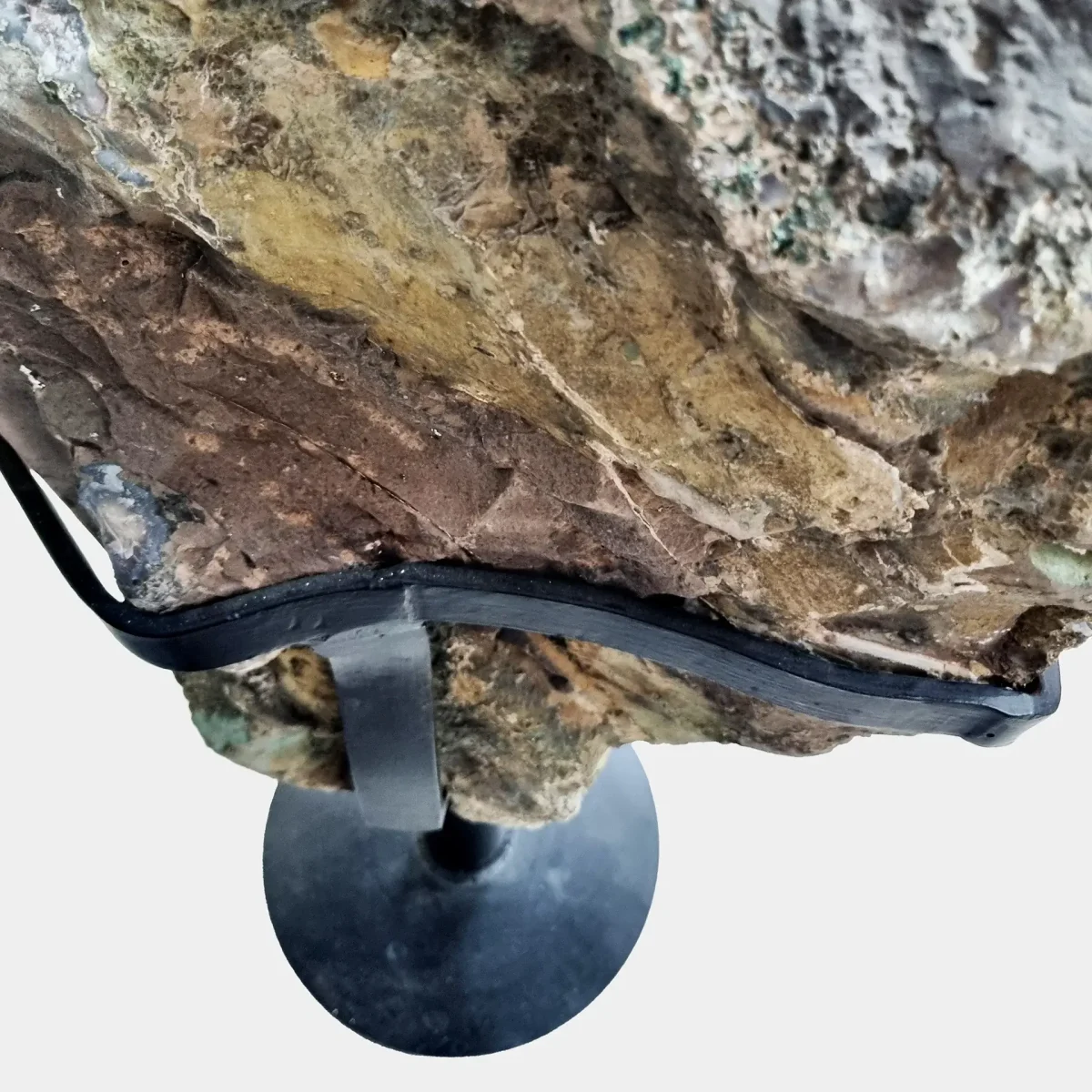 Pogled na zadnjo, naravno mineralno površino geode ter črno kovinsko stojalo, ki ji nudi stabilno in diskretno oporo.