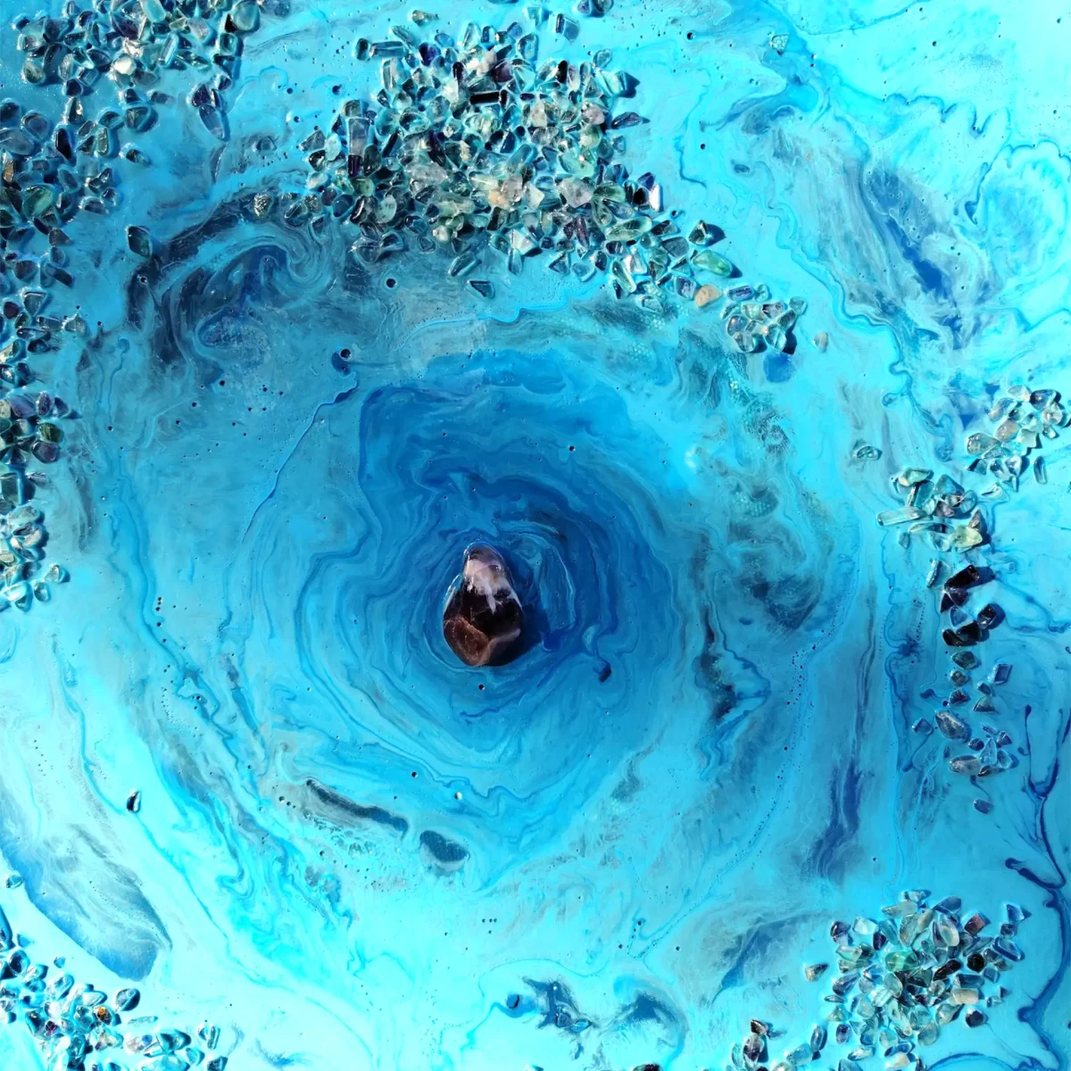 Central detail with circular blue movement and a polished stone at the centre