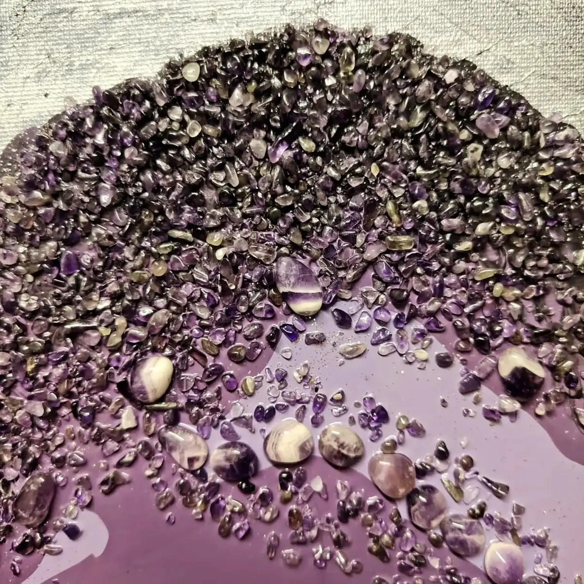 Close-up of dense amethyst crystal chips forming the upper edge of the geode-shaped composition