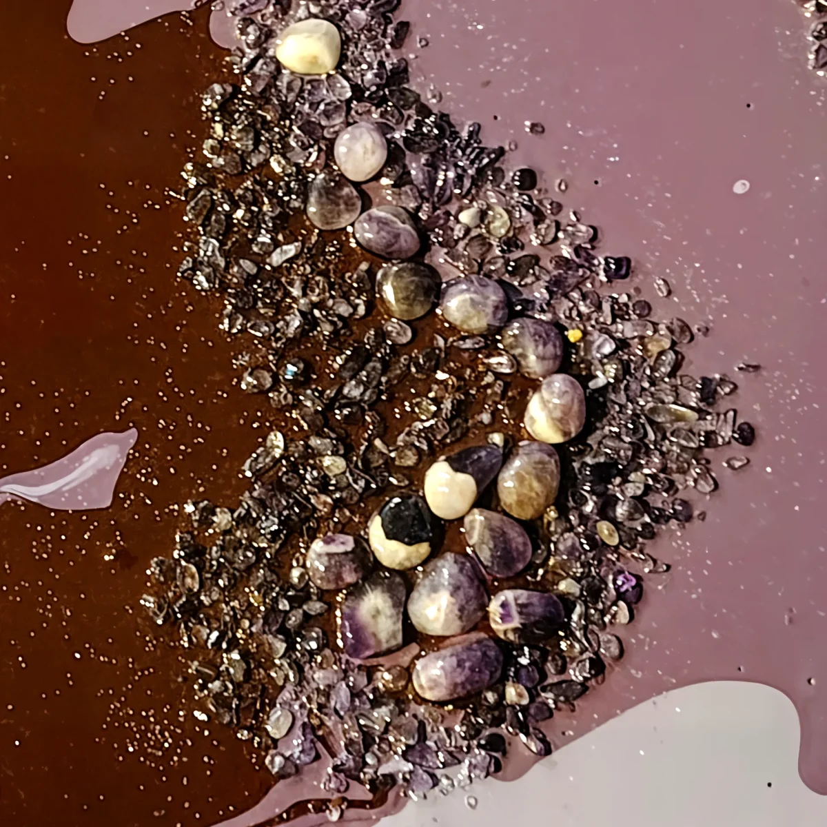Detail of polished banded amethyst stones embedded among crystal fragments in purple and brown resin