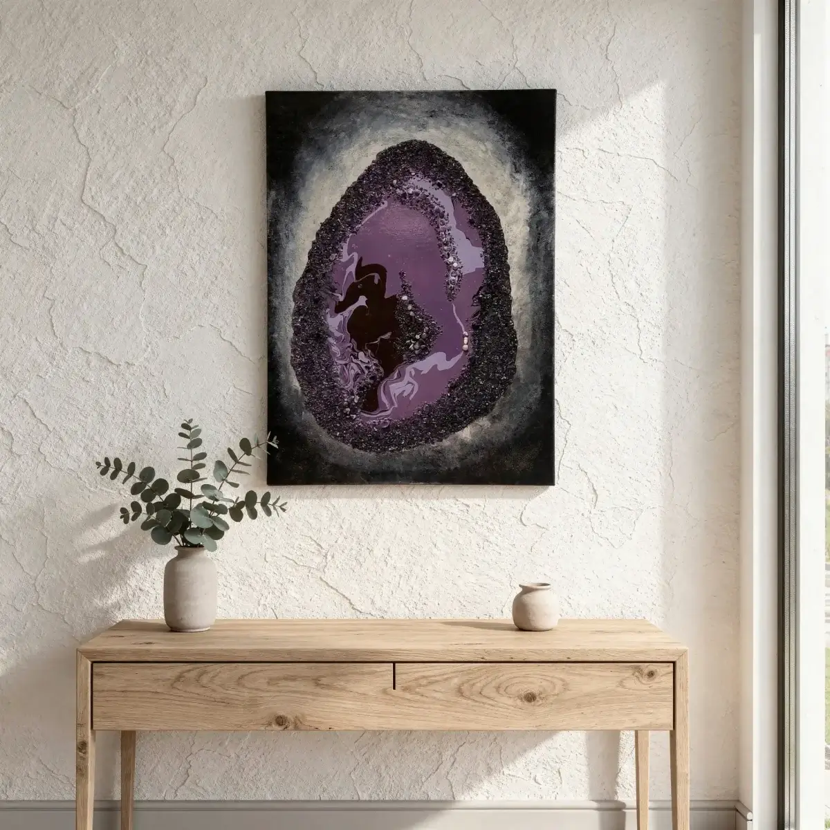 Amethyst and the Birth of the Seahorse crystal painting by Nóra Baka displayed above a light oak console table with a ceramic vase and eucalyptus branches in a minimalist Scandinavian interior