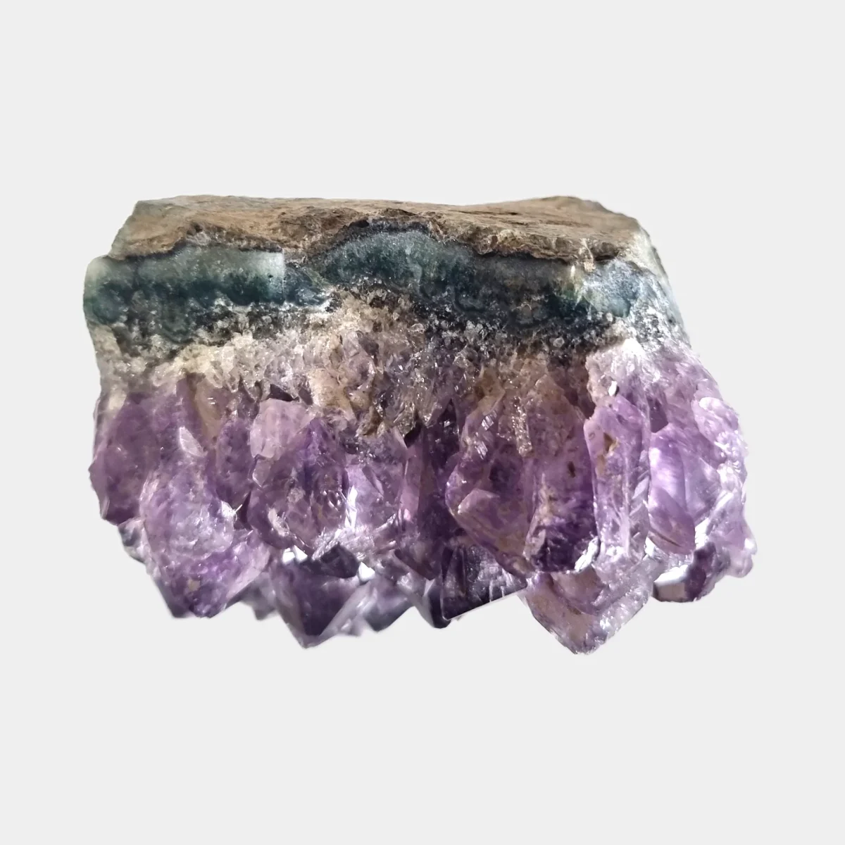 Top view of an amethyst cluster showing purple crystal points beneath the natural stone edge.