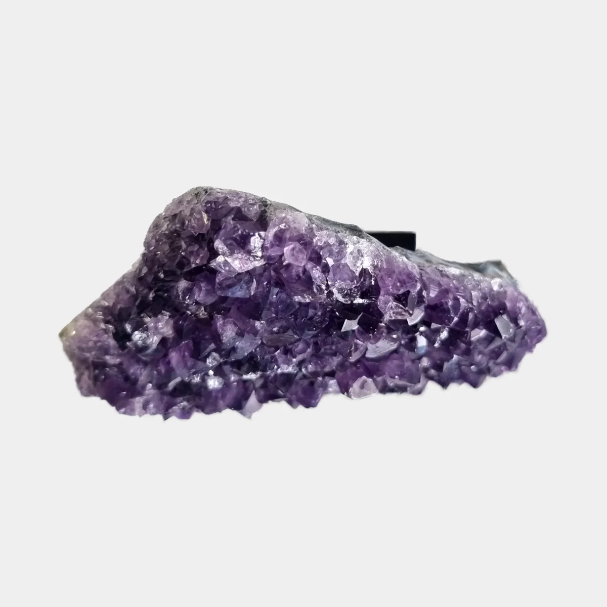 Top view of an amethyst cluster showing purple crystal points and the natural stone edge.