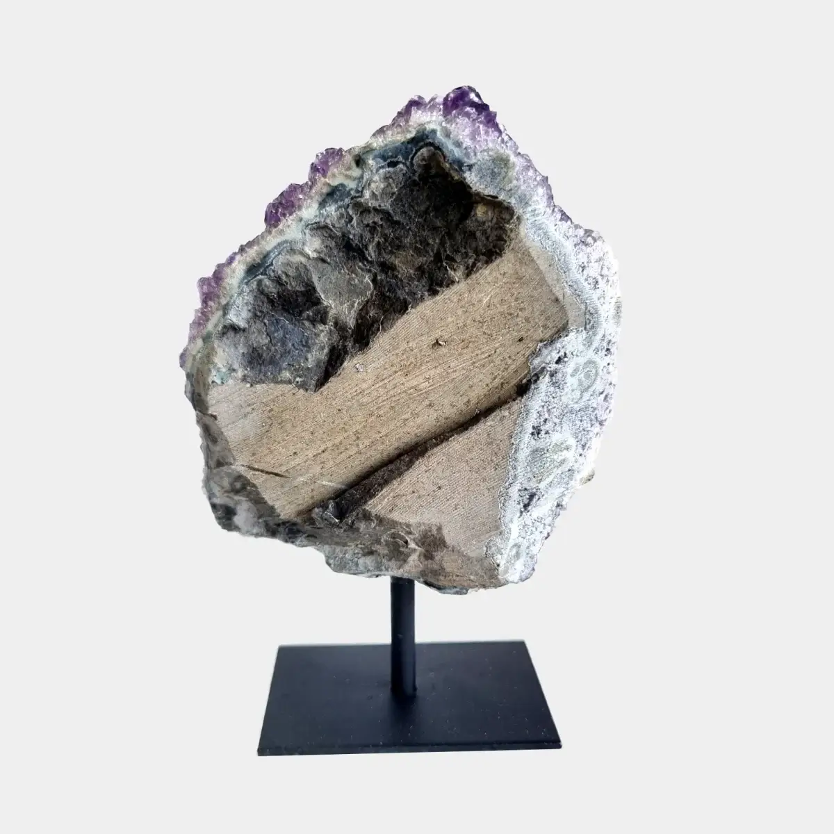 Back view of an amethyst cluster on a black metal stand showing the cut natural stone exterior.