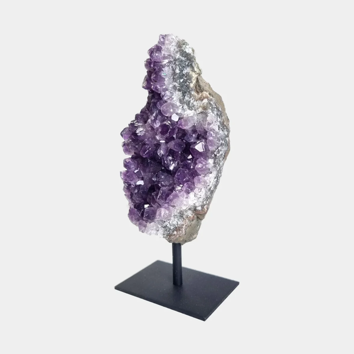 Angled front view of an amethyst cluster on stand with purple crystals and pale natural stone edges.