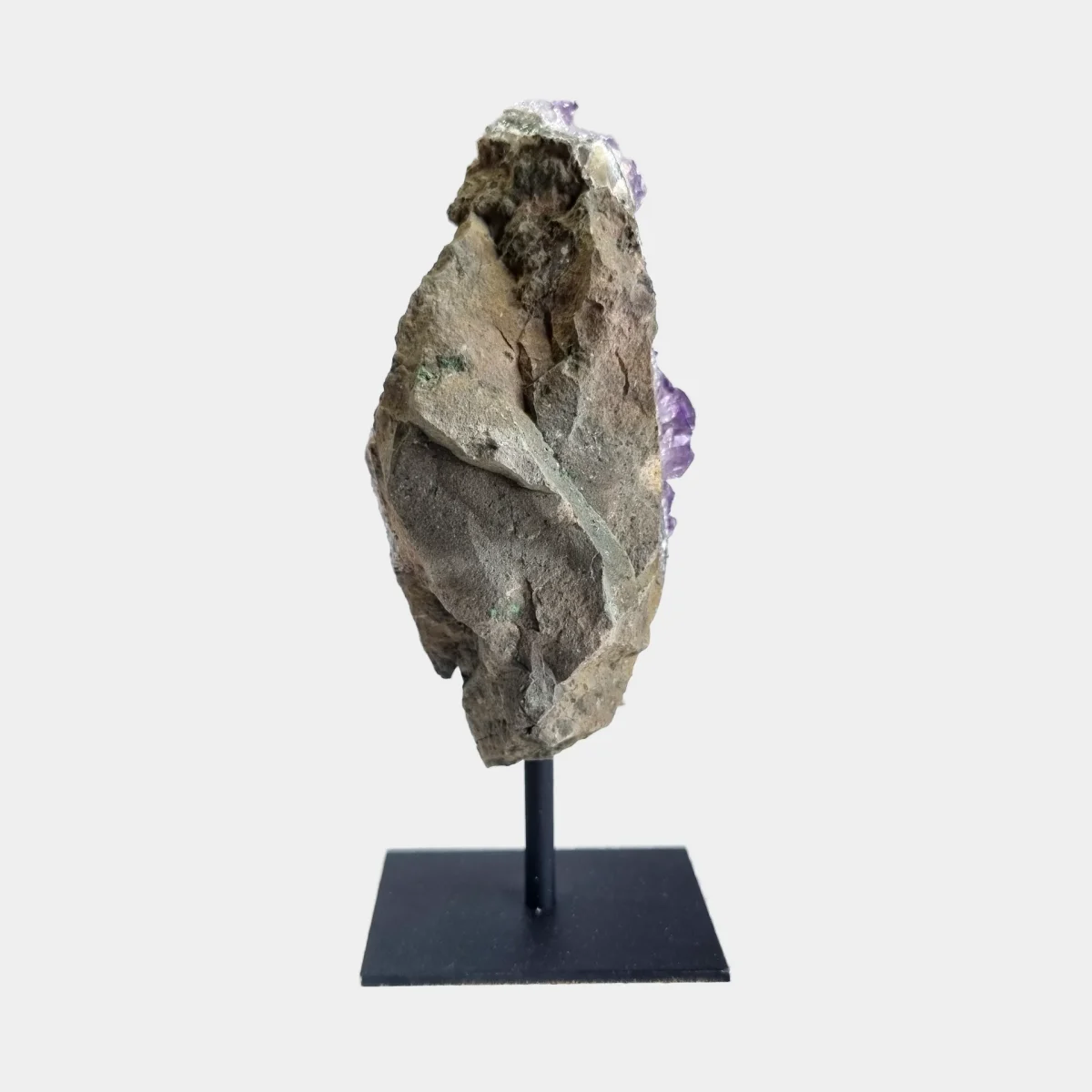 Back view of an amethyst cluster on a black metal stand showing the natural stone exterior.