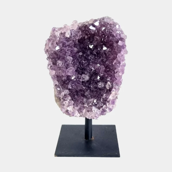 Front view of an amethyst cluster on a black metal stand with pale violet crystals and a compact shape.