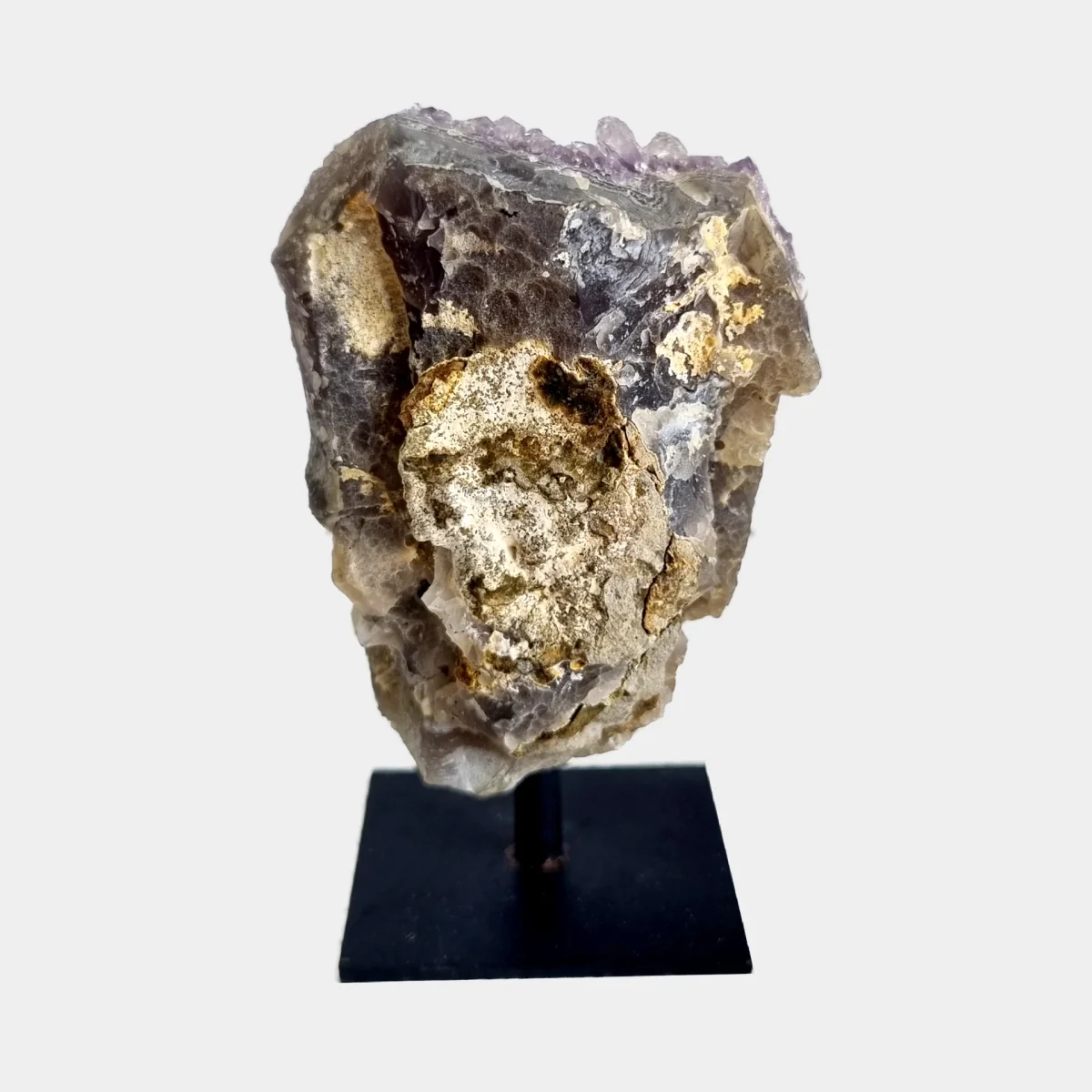 Back view of an amethyst cluster on a black metal stand showing the natural stone exterior.