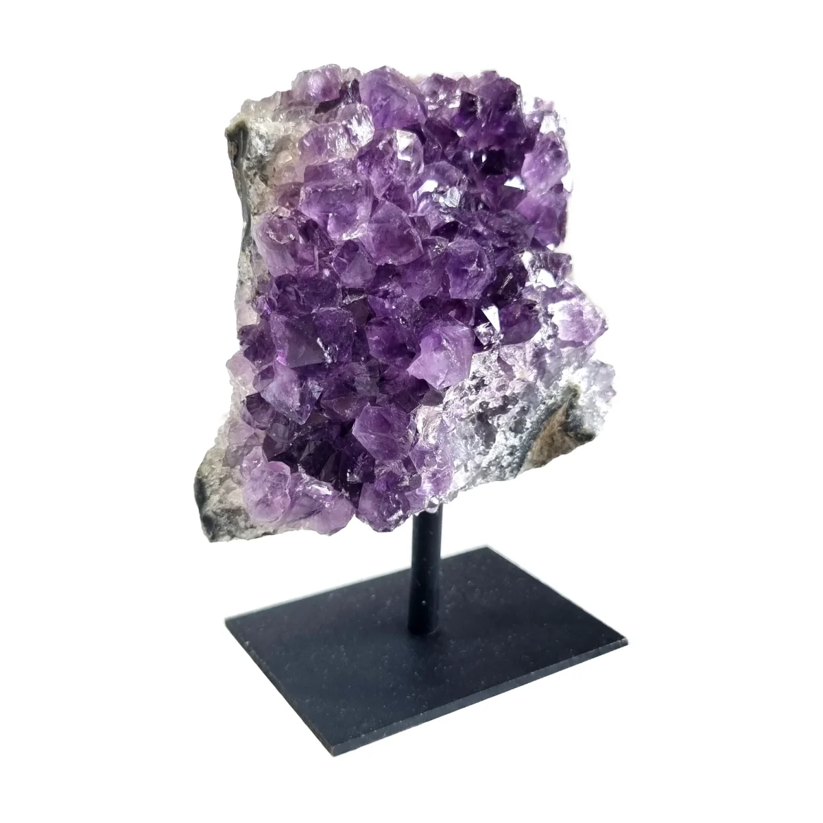 Side angle view of an amethyst cluster on a black metal stand showing purple crystals and natural stone.