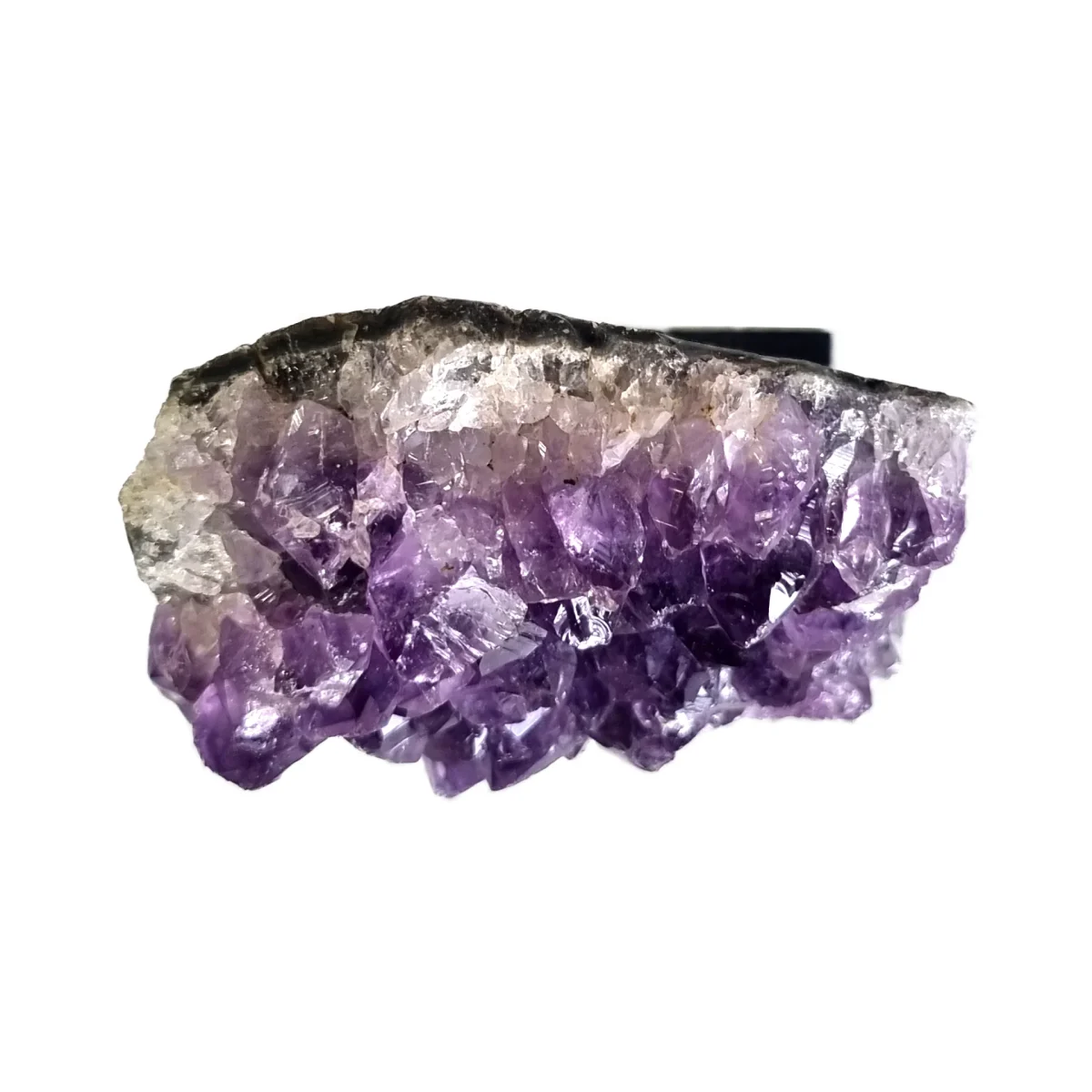 Side view of an amethyst cluster showing purple crystal points beneath the natural stone edge.
