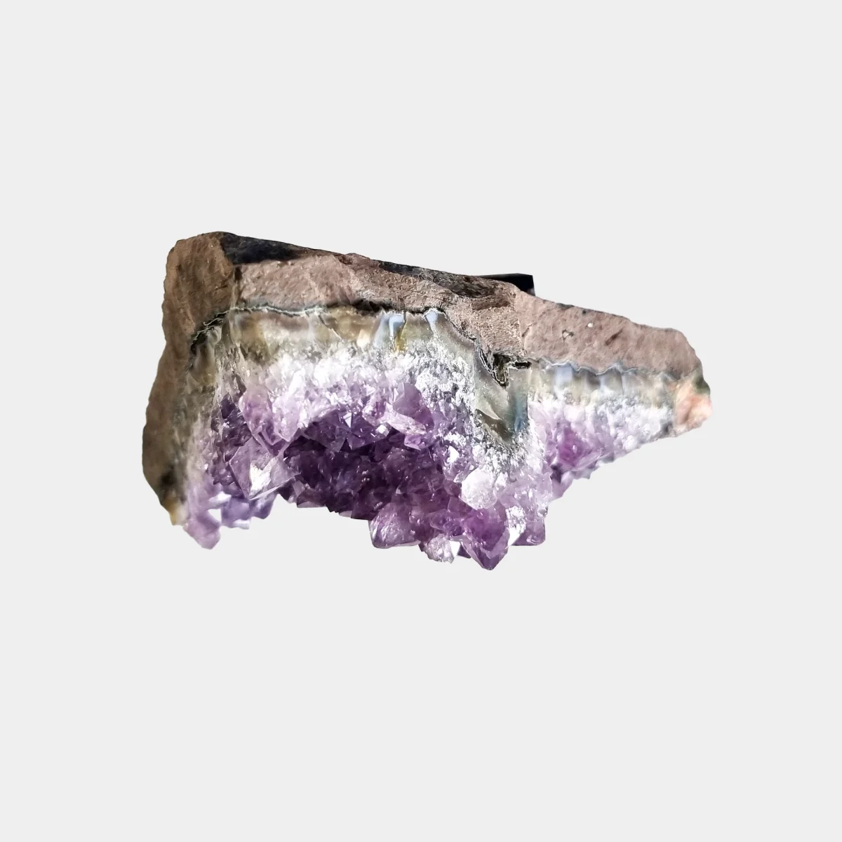 Top detail view of an amethyst cluster showing layered natural stone and violet crystal points.