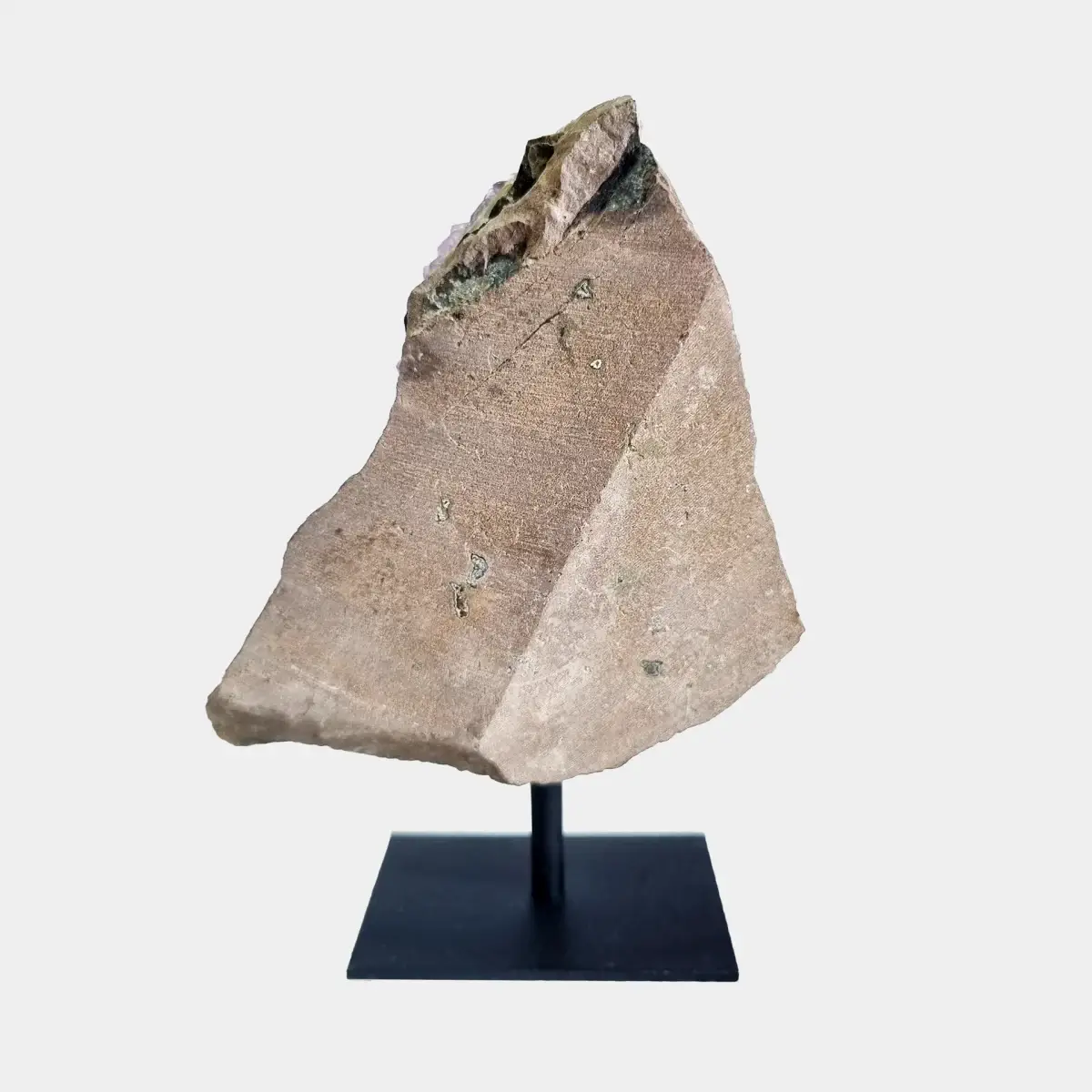 Back view of an amethyst cluster on a black metal stand showing the cut natural stone exterior.