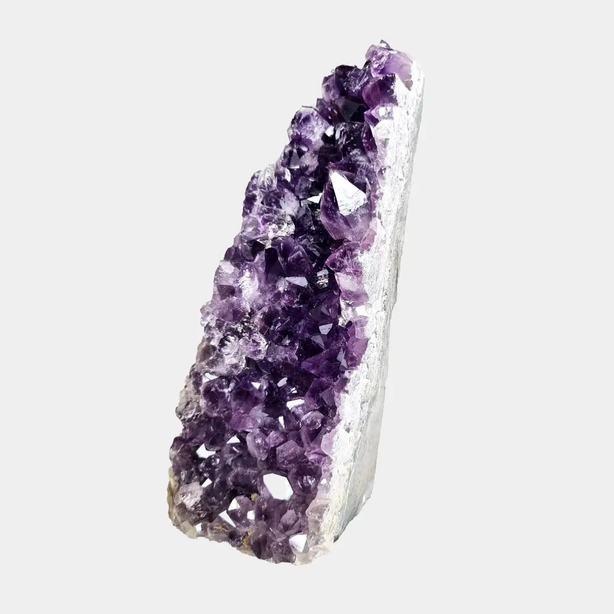 Angled front view of a small amethyst geode with deep purple crystals and a pale quartz edge.