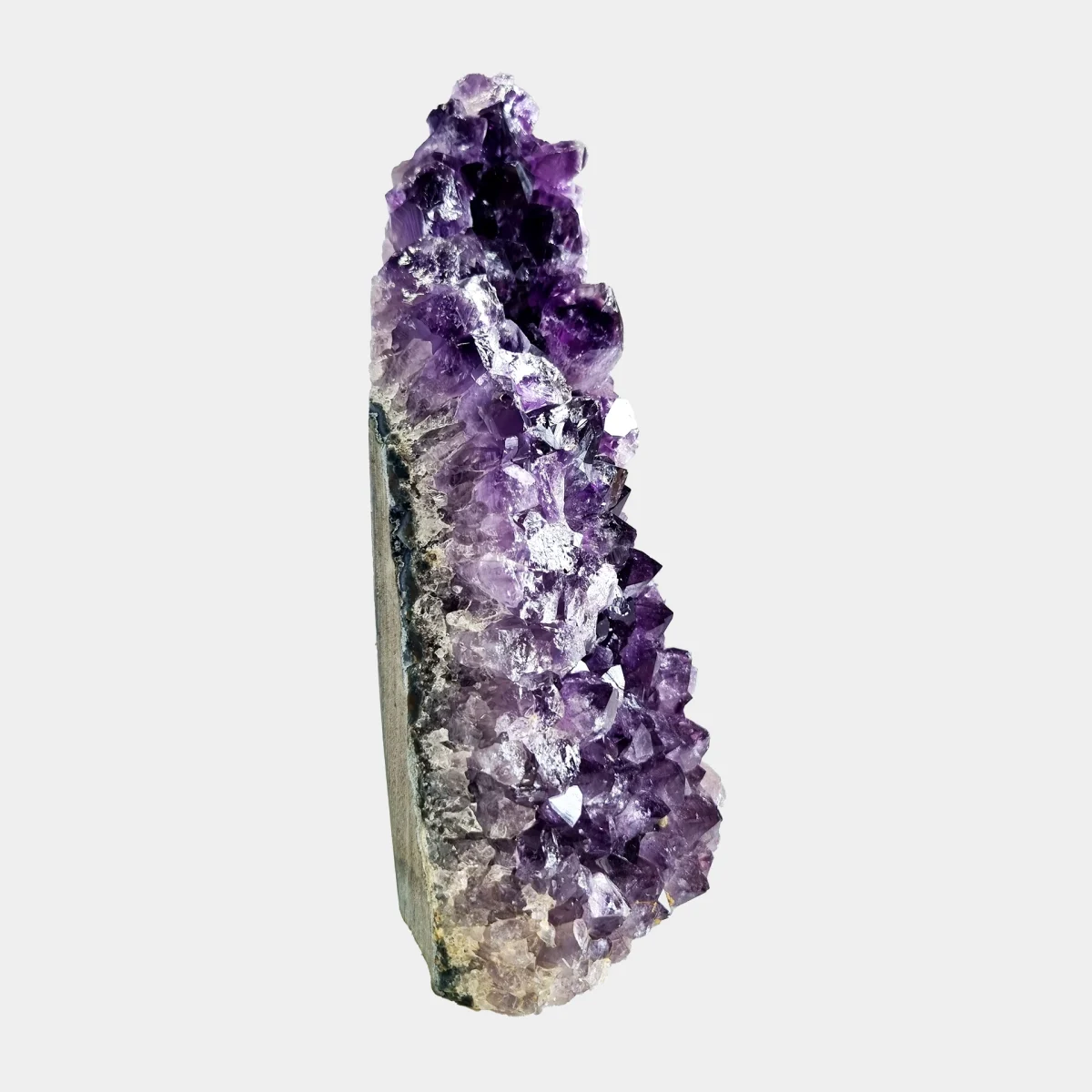 Side view of a small amethyst geode showing tall violet crystals and the natural stone base.