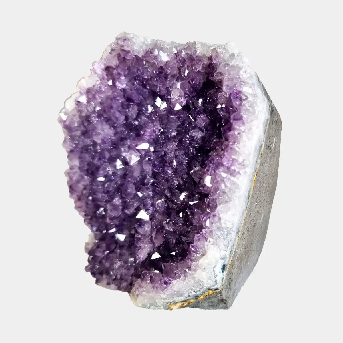 Side view of a small amethyst geode showing violet crystals, white quartz, and the cut stone exterior.