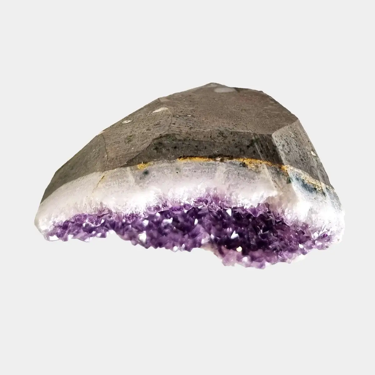 Top view of a small amethyst geode showing the cut stone exterior above a narrow line of purple crystals.