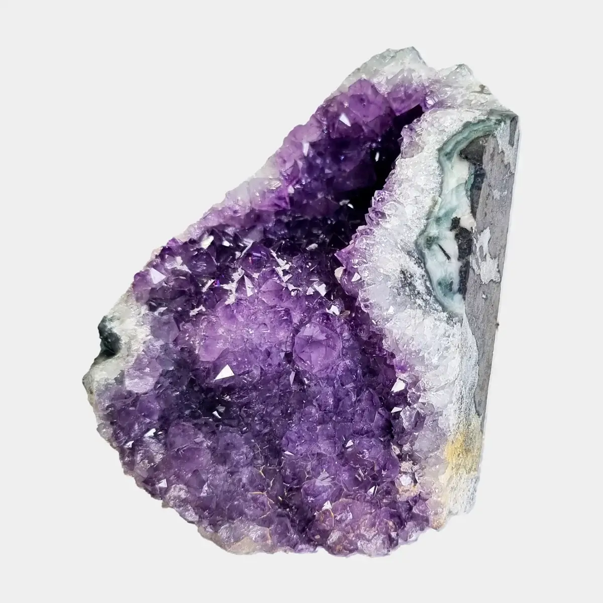 Angled front view of a small amethyst geode with purple crystals, pale quartz, and a visible cut stone side.