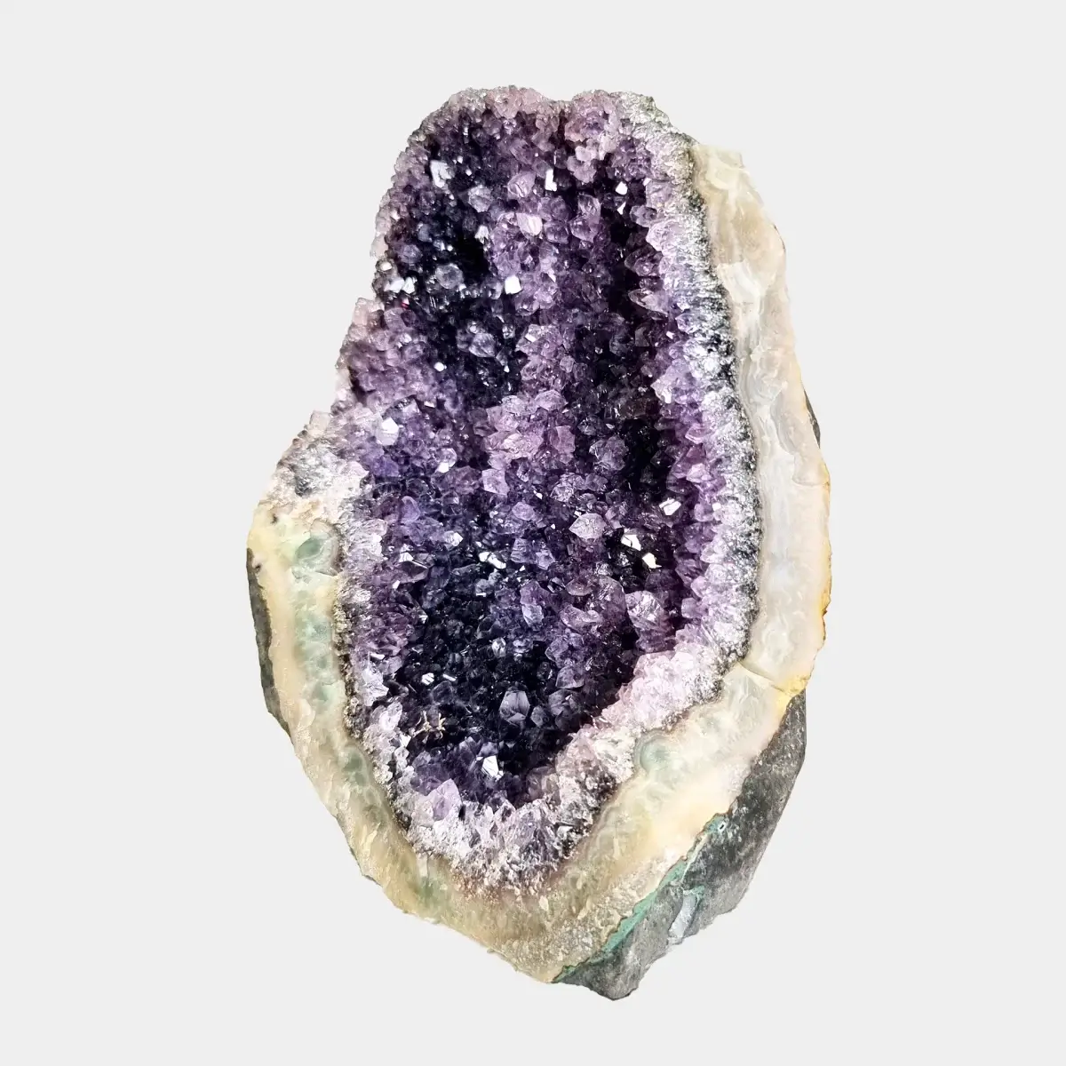Angled front view of a small amethyst geode with deep purple crystals and pale quartz around the opening.